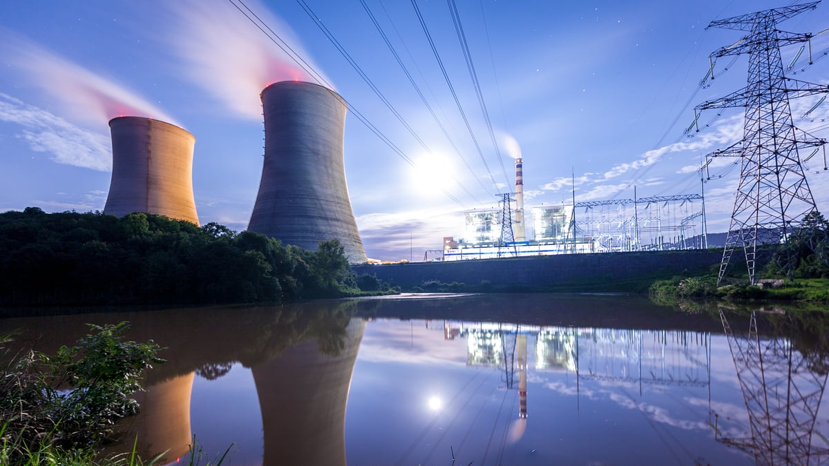 Image shows two cooling towers at an energy facility against a blue sky backdrop.
