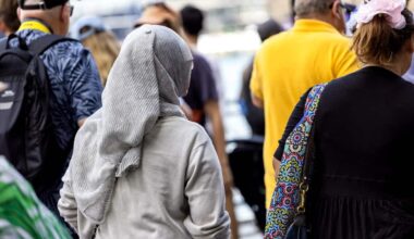 Rear view of woman wearing hijab walking in crowd of people