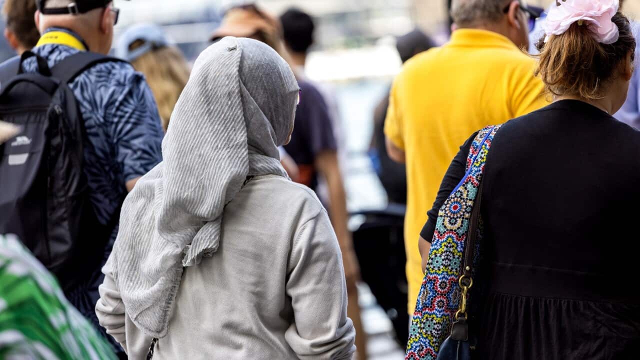 Rear view of woman wearing hijab walking in crowd of people