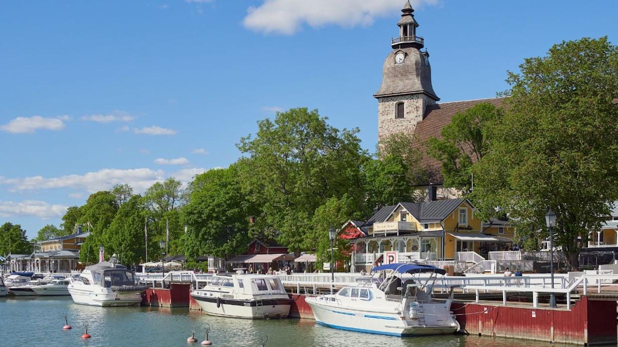 Finland, Naantali - June 9, 2023. Embankment in the old center of the Finnish town of Naantali in Europe: Lutheran church, old wooden houses, yachts.