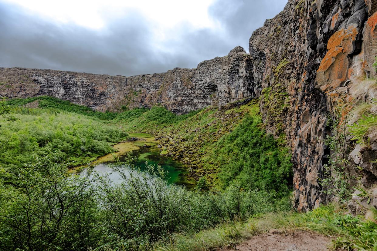 View at Asbyrgi Glacial Canyon in Northern Iceland, Asbyrgisskogur forest and Botnstjorn lake surrounded by steep cliffs.