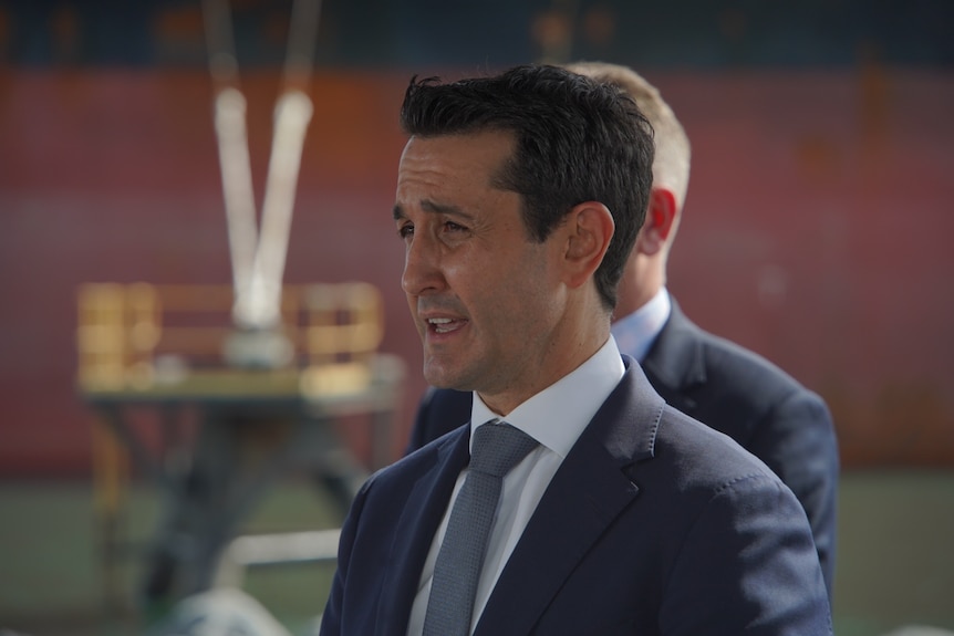 A man in a suit standing in side profile speaking.