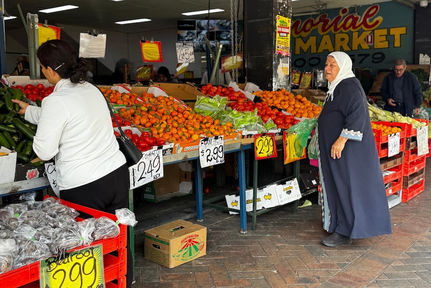 Two women stood outside a fruit shop.