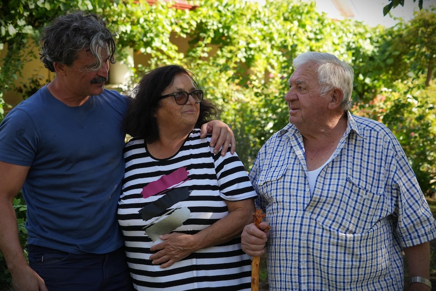 three people stand together with a sombre look