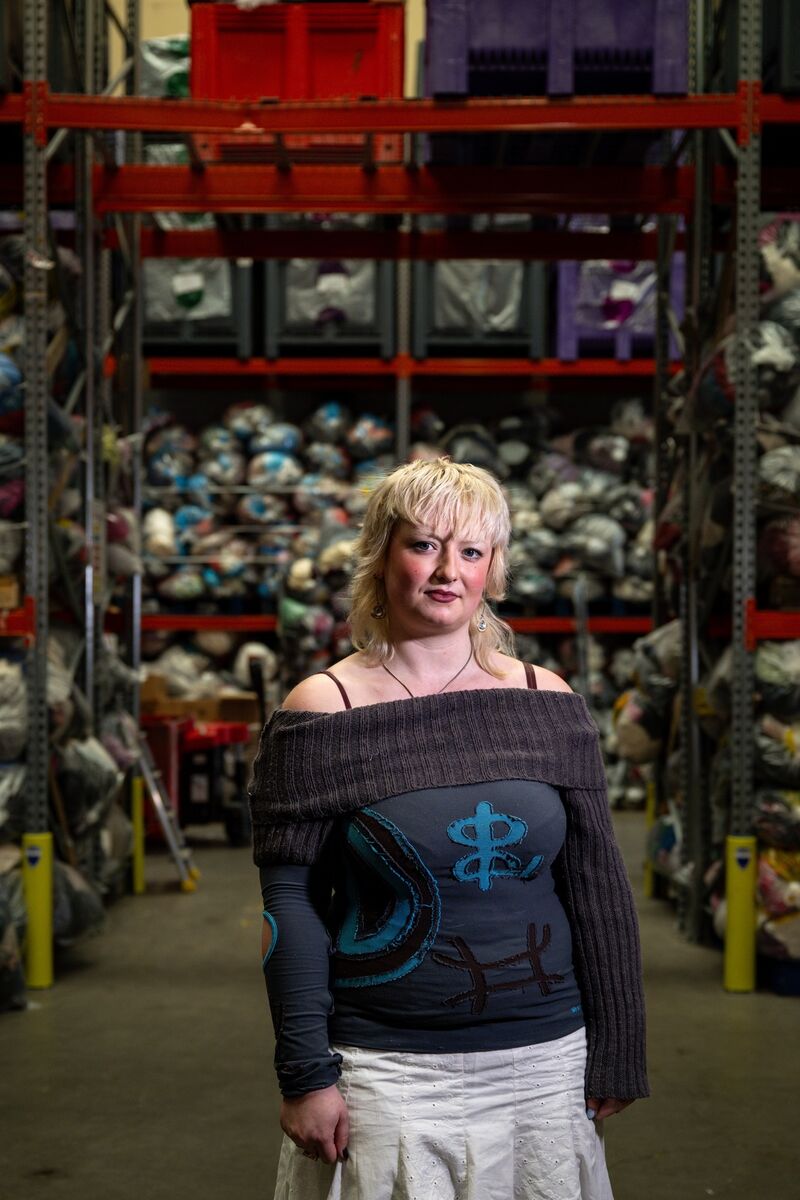 Holly Warren stands before more than 10,000 bags of donated clothing 
