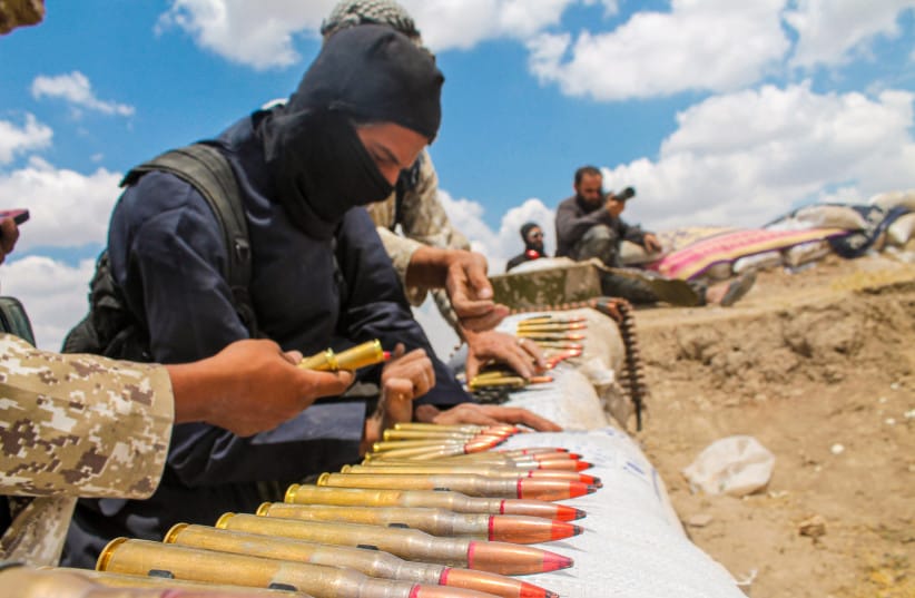 A soldier in an ISIS uniform prepares ammunition.