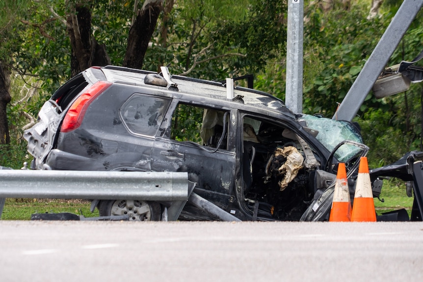 A burnt car that has crashed into power pole