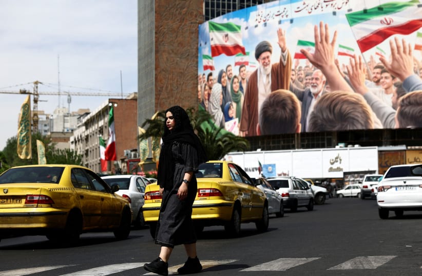 A woman walks past a billboard featuring an image of the late Supreme Leader of Iran, Ayatollah Ali Khamenei, on a building, amid a ceasefire between US and Iran, in Tehran, Iran, April 27, 2026