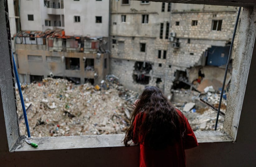 Alaa Dahnoun, 12, who said she survived an Israeli strike that forced her to flee with her parents to Beirut, looks out through her apartment's damaged window after a 10-day ceasefire between Lebanon and Israel went into effect, in Nabatieh, Lebanon, April 18, 2026.