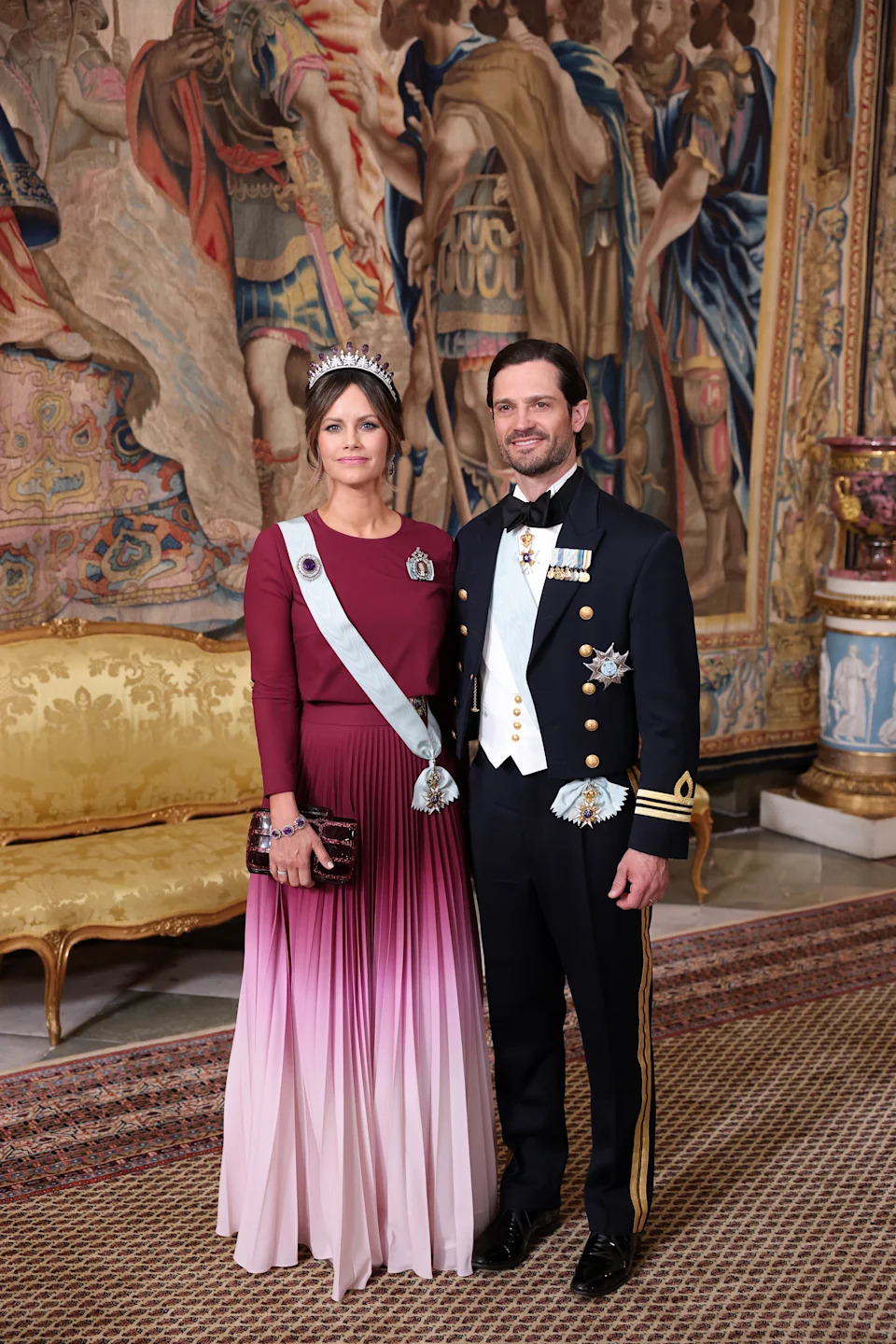 Princess Sofia and Prince Carl Philip in evening wear standing in front of a tapestry