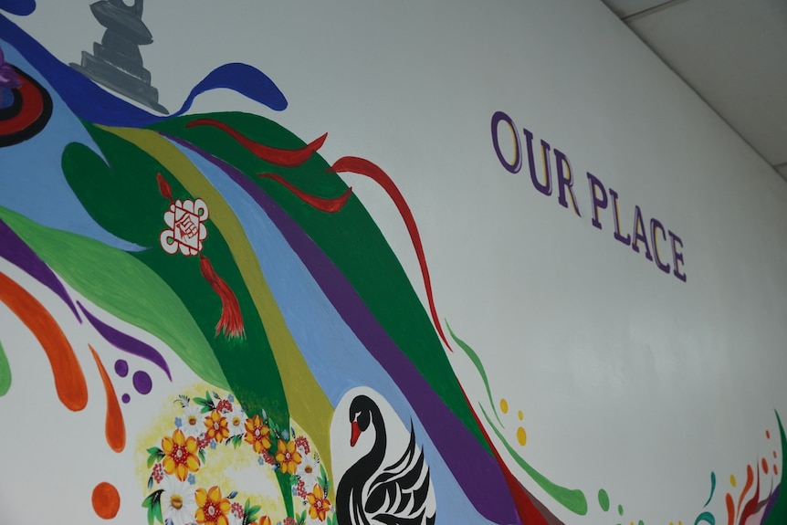 A sign reading "Our Place" is on a colourful wall