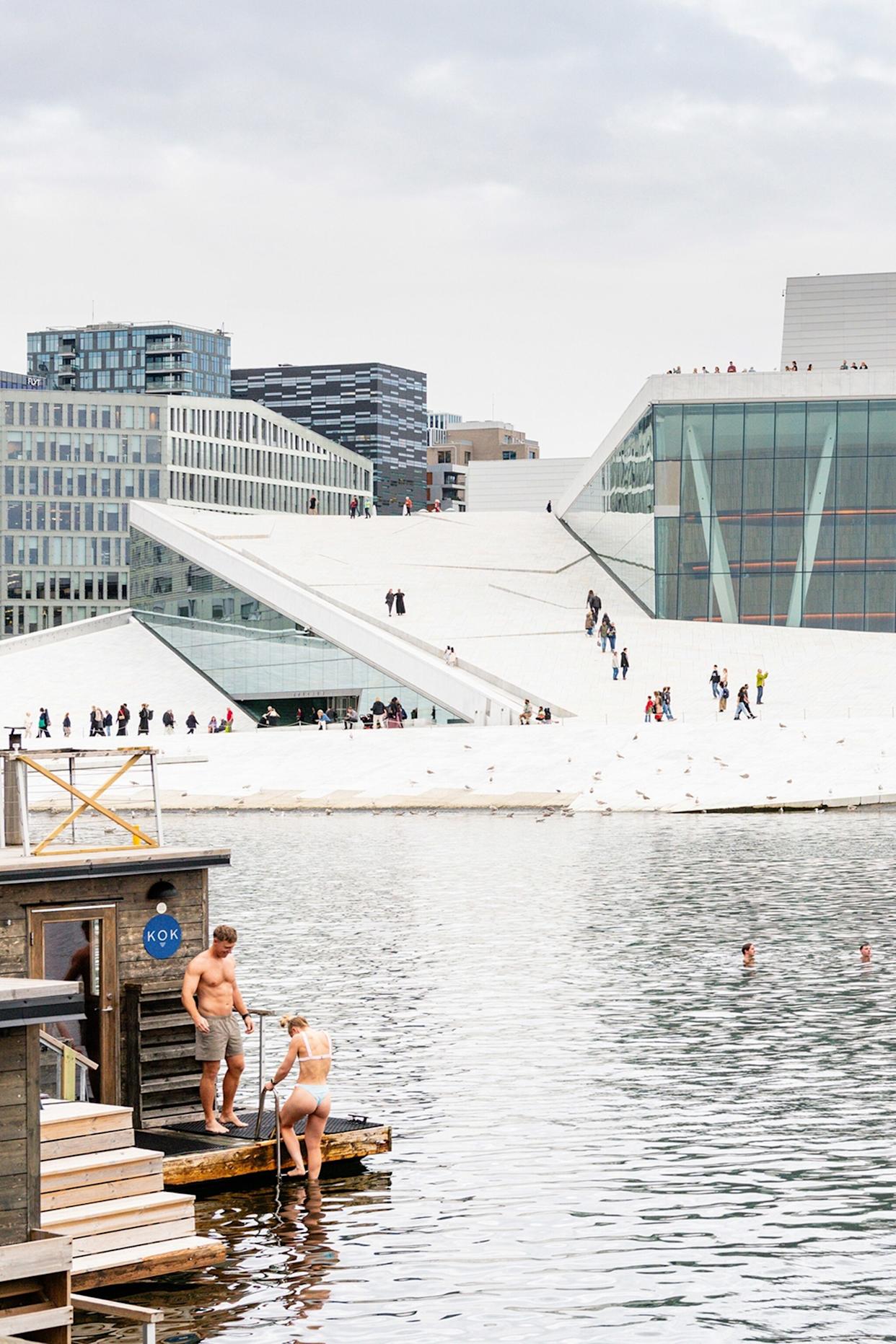People going swimming at a harbour promenade on a cloudy day.