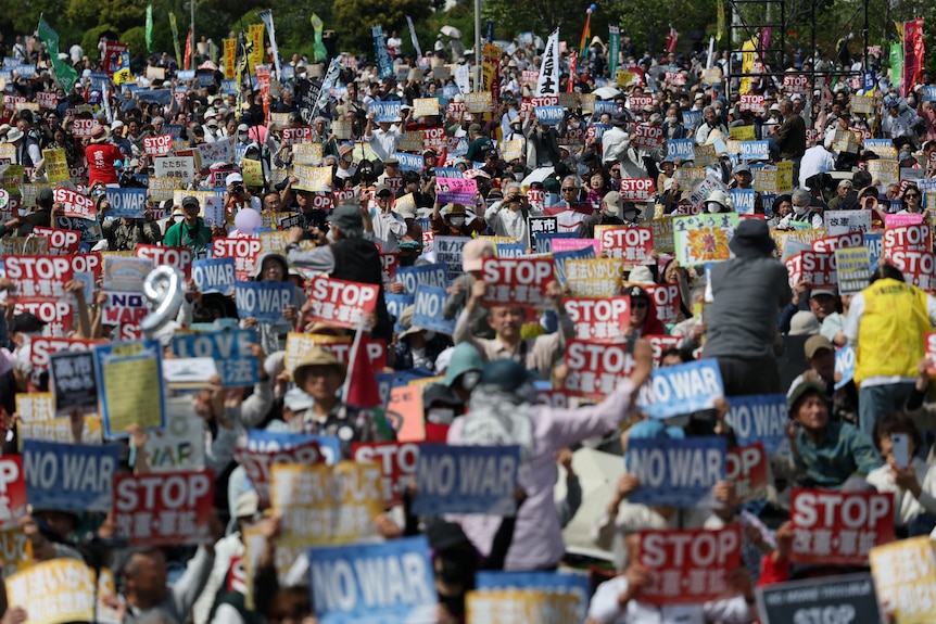 Participants and protesters hold posters opposing Japan's Prime Minister.