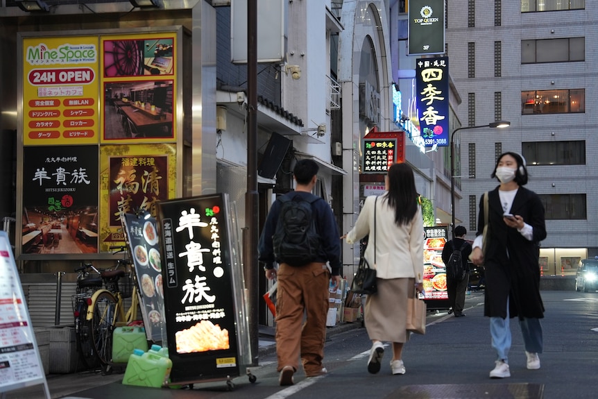 Locals walk along a busy restaurant strip in Tokyo.