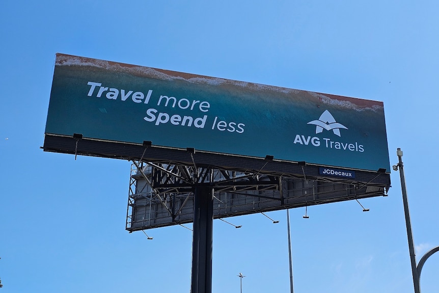 A large advertising sign saying "Travel more, spend less" and the AVG Travel logo.