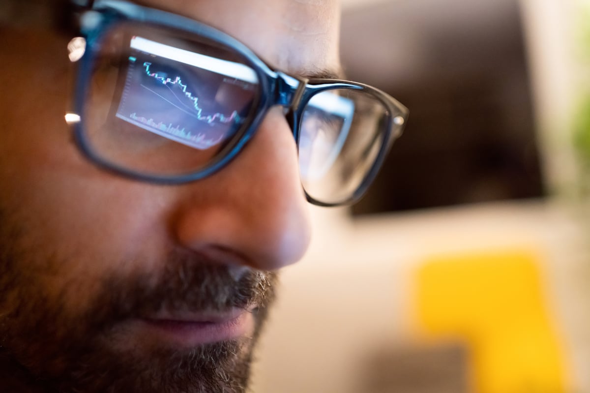 Close-up of a person's face, as they look at a stock chart.