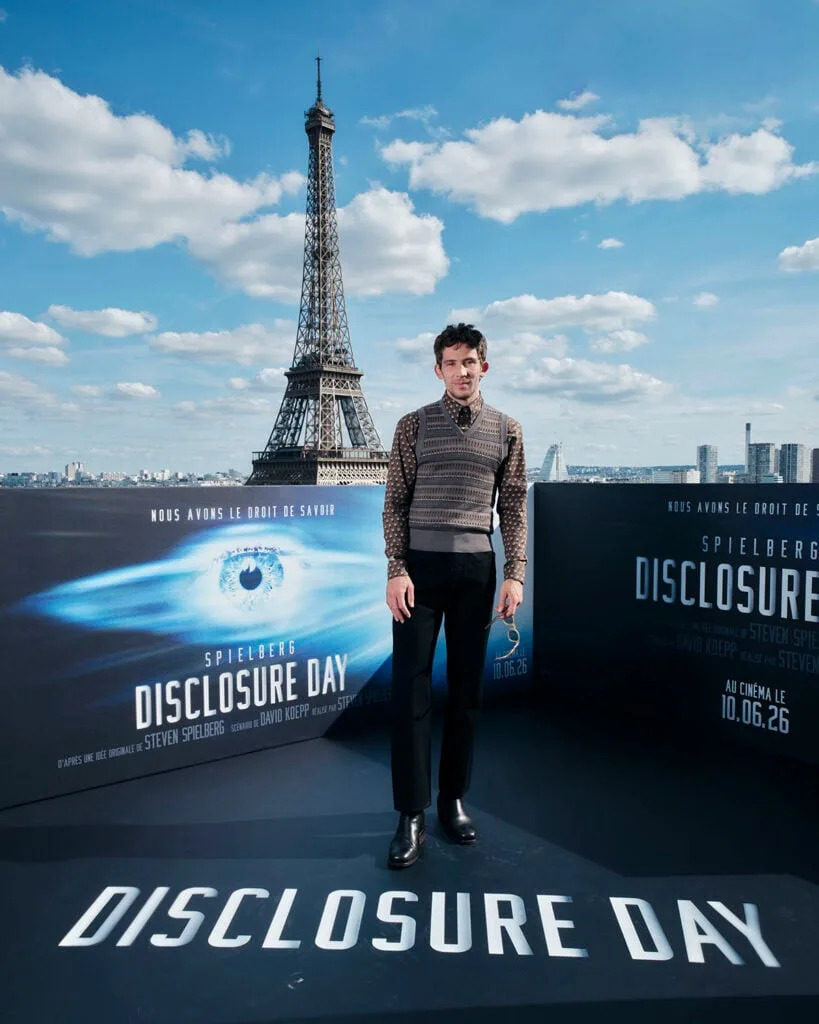 Josh O’Connor poses in a patterned shirt, knit vest and tailored trousers at the Disclosure Day Paris photocall.