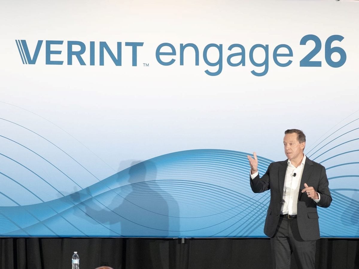 Verint CEO Dave Rhodes on stage at Verint Engage 2026 with "Verint Engage 26" written on a blue and white backdrop.