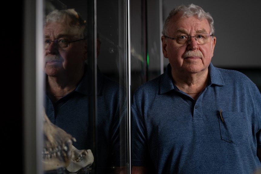 A man with a moustache and glasses standing in a university lab.