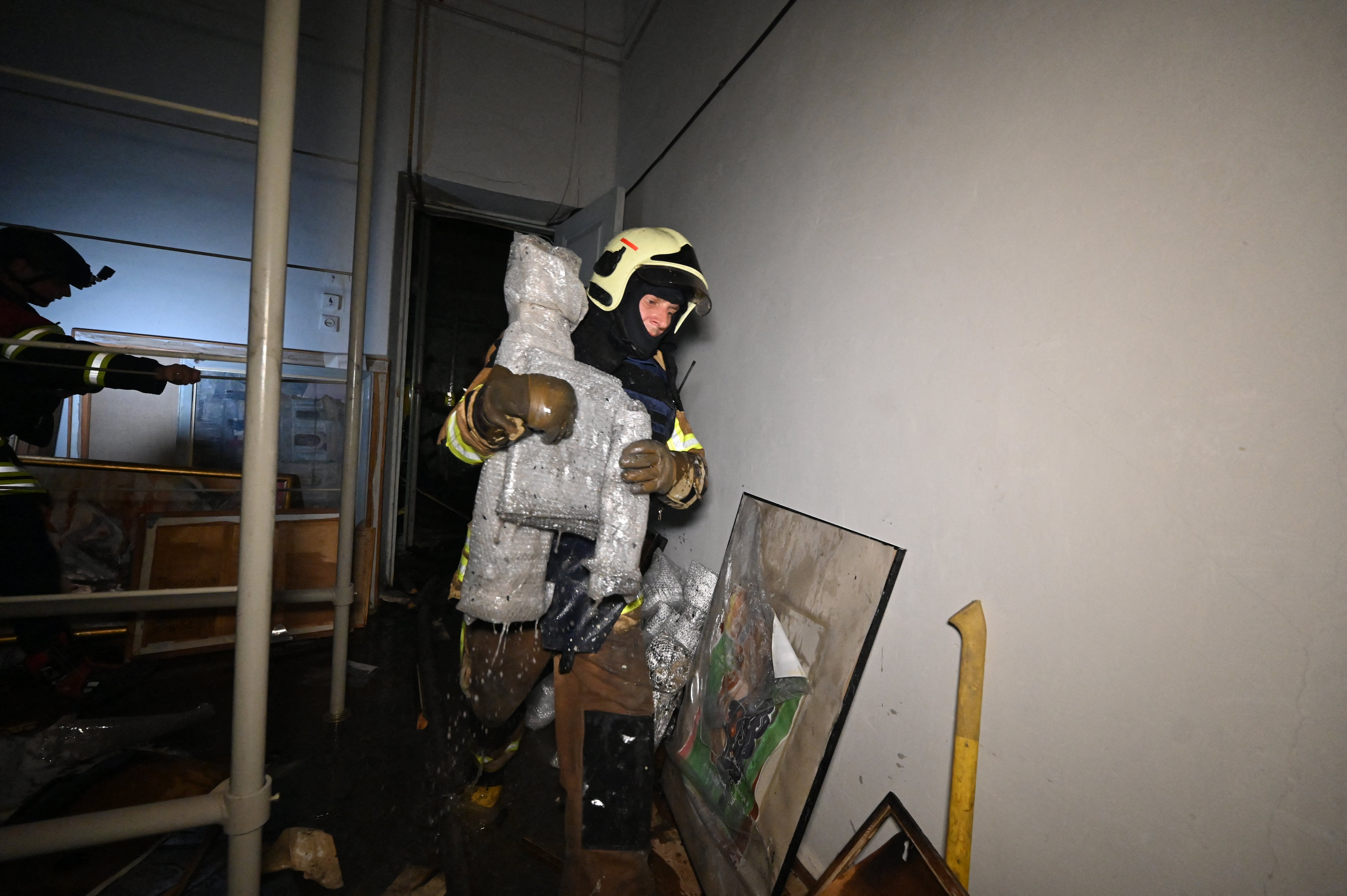 A firefighter walks past damaged paintings at the damaged Kharkiv Art Museum following a drone strike in Kharkiv