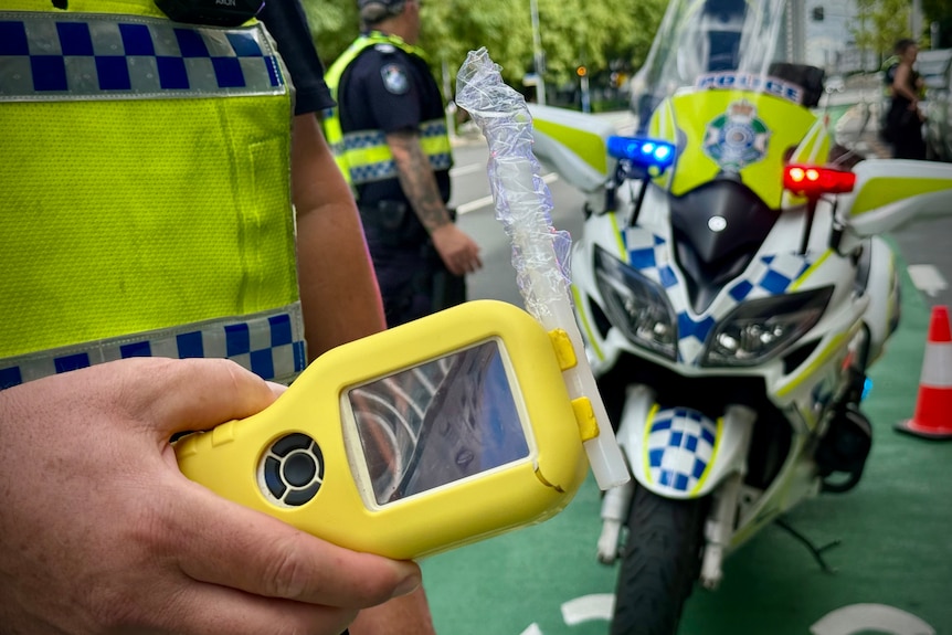 Queensland police holding breath testing units while pulling over drivers