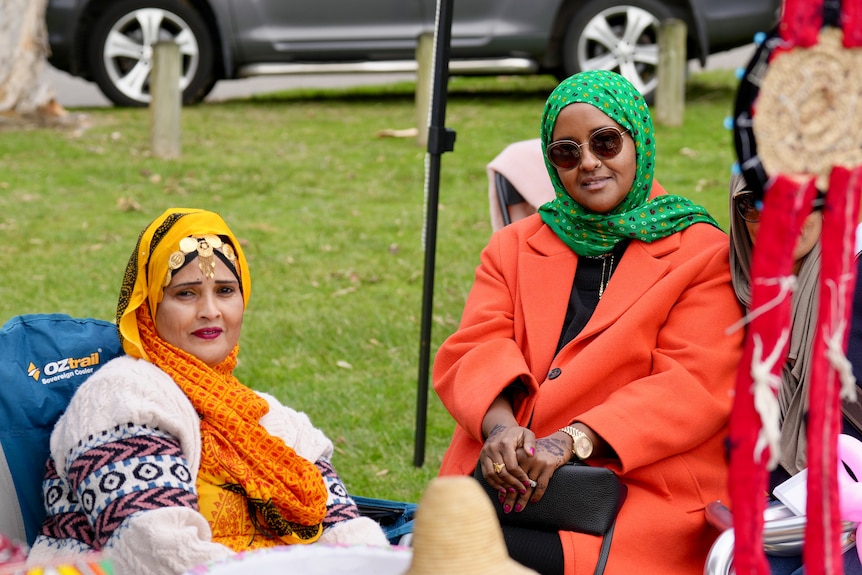 Ladies with head scarves watch a soccer match.