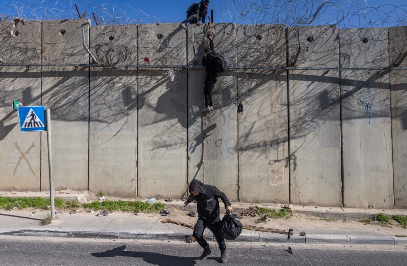 Palestinians use a rope to climb over the separation barrier from the al-Ram village into the East Jerusalem neighborhood of Beit Hanina, December 23, 2025