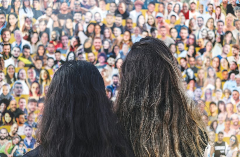 Israeli women gaze at Nova victims poster.