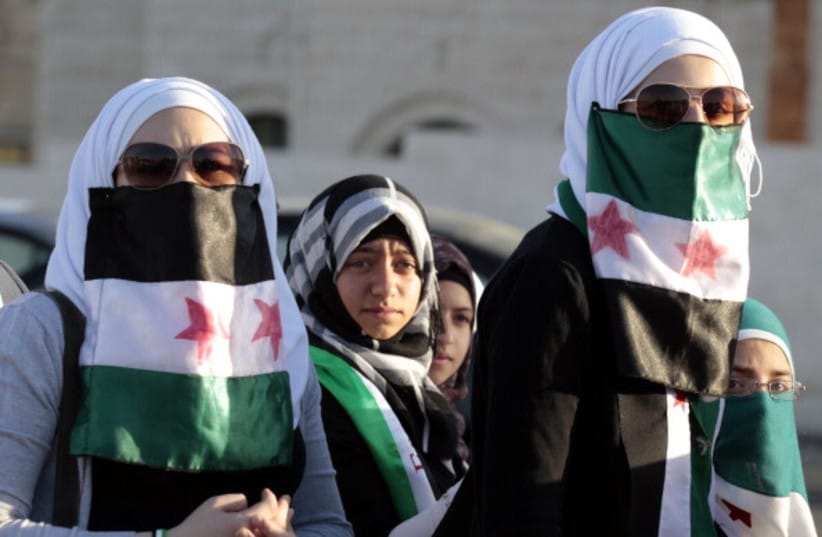 Syrian women living in Jordan use the old Syrian flag adopted by the Syrian opposition groups to cover their mouths during a demonstration against Syria's President Bashar al-Assad and his regime as they gather in front of the prime minister's offices in Amman on June 13, 2012.