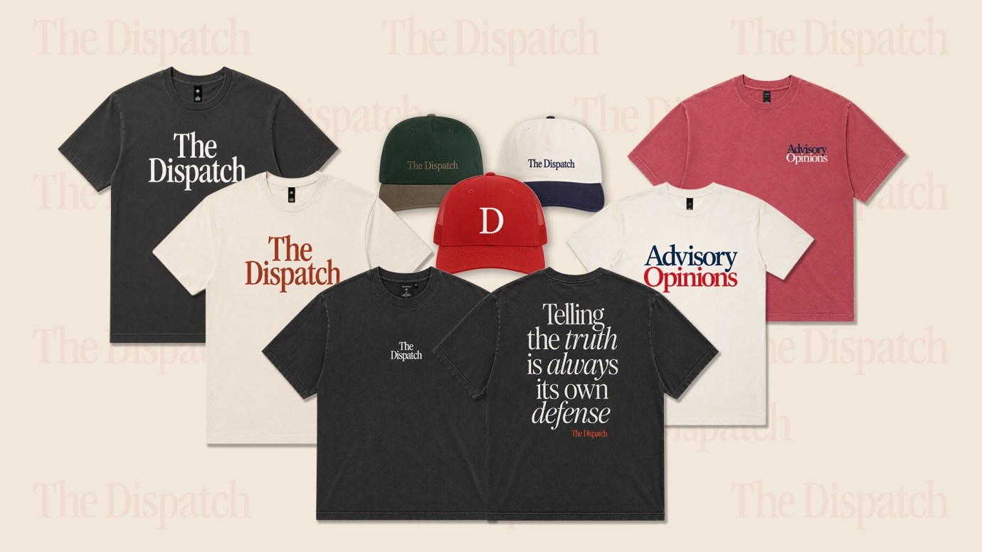 Dispatch-Banner-1920x1080 A collection of The Dispatch branded merchandise including t-shirts in black, white, and red, baseball caps in various colors, and a red cap with a "D" logo, arranged against a beige background.