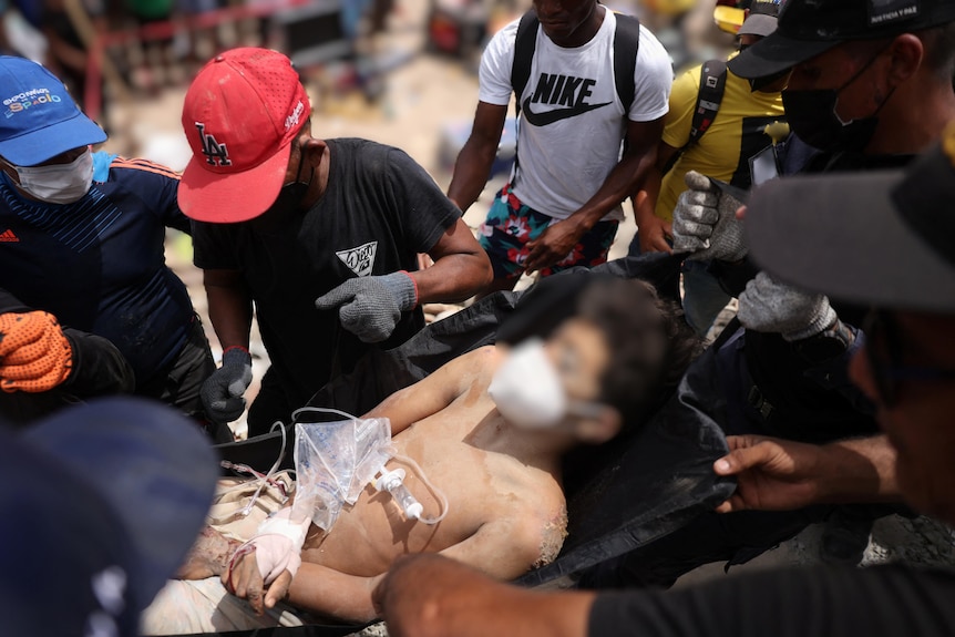 A boy on a stretcher with medical equipment, surrounded by people