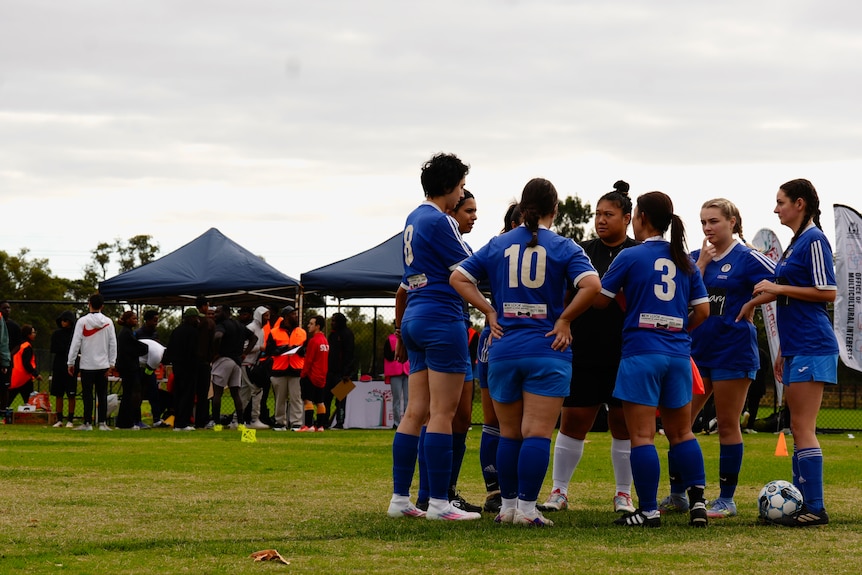 A team huddles on a soccer field.