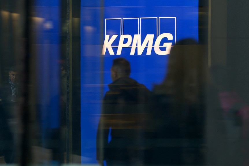 People silhouetted against a white and blue KPMG logo.