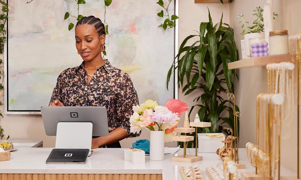 Person using Square device behind counter while Square device logo is in view.