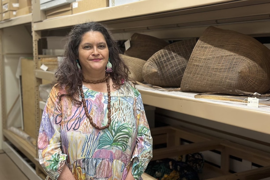 a smiling woman next to shelves of woven baskets.