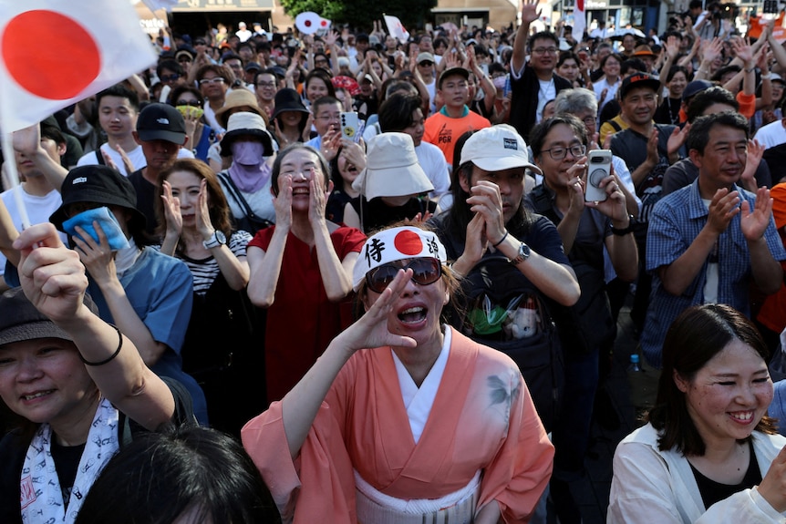 Supporters of the Sanseito party, including one person wearing a head band with the Japanese flag, rally.
