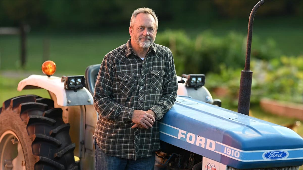 Peter Oberacker stands in front of a tractor.