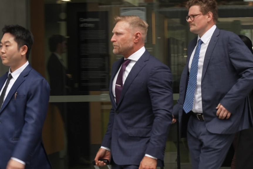 Three men in suits walking out of court.