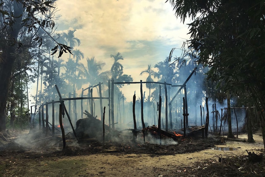 Smoke rises from the remains of a house destroyed by fire