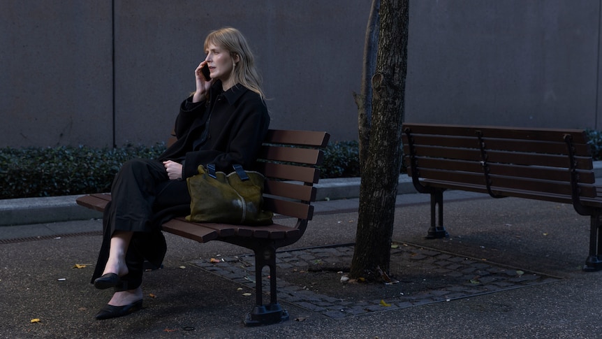 A lawyer on the phone sitting on a bench.