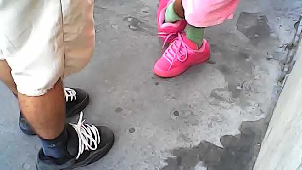 A person in black shoes, left, and a person in pink shoes