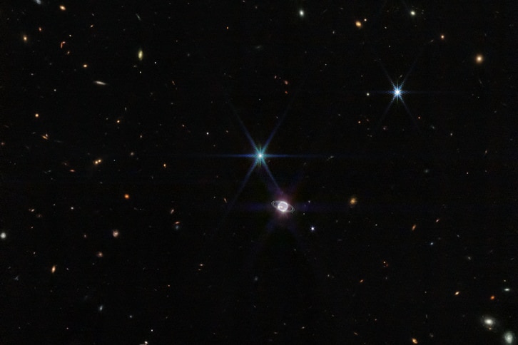 A wide-angle image of neptune and Triton againsta black galaxy.