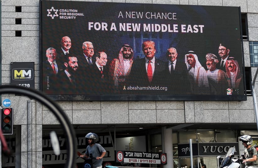 People walk by a billboard sponsored by the Coalition for Regional Security calling for the expansion of the Abraham Accords, in Ramat Gan