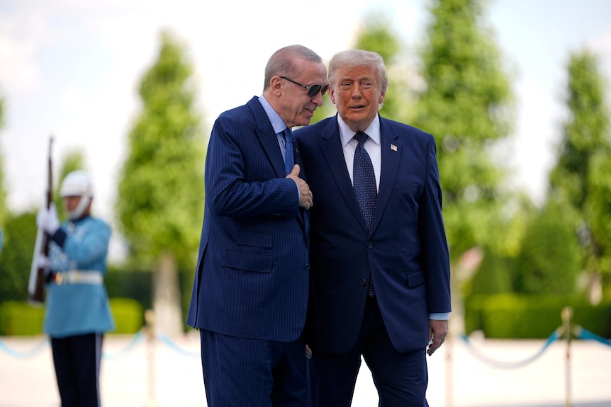 Donald Trump stands close to another man and appears to whisper in his ear.