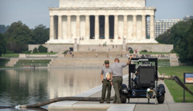 National Park Service workers stand near a pump placed next to the Lincoln Memorial Reflecting Pool, Friday, July 10, 2026, in Washington. (AP Photo/Mark Schiefelbein)