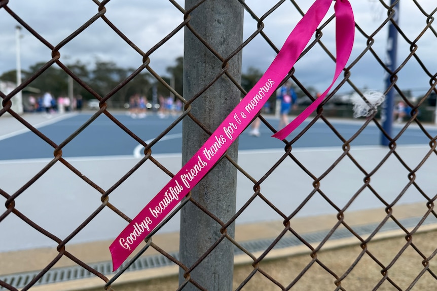 A pink ribbon on a chain link fence