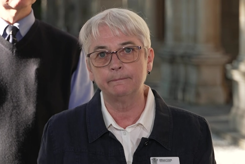 A woman with white hair and glasses