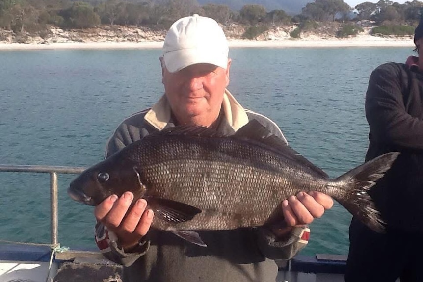 A man holds a fish.