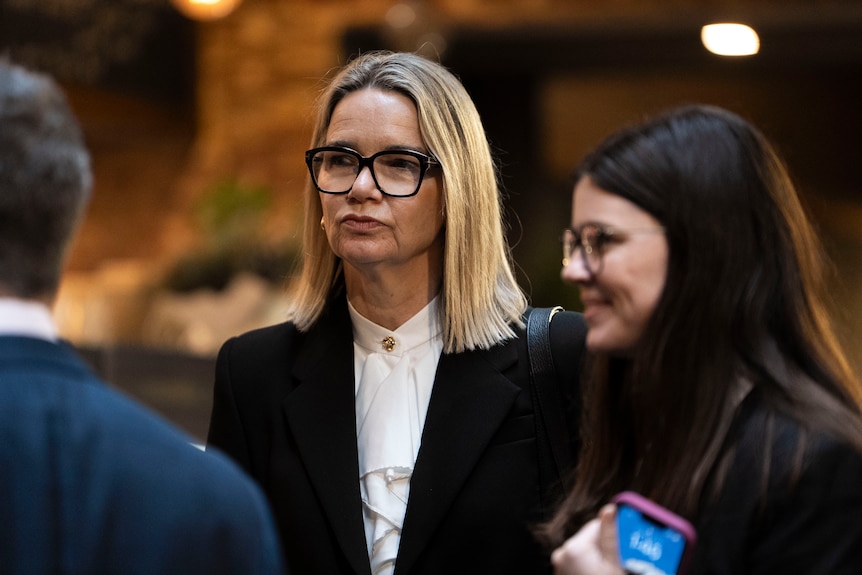ABC ombudsman Fiona Cameron in glasses and a black blazer, with blonde hair, outside the commission.
