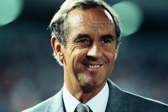 A photo of John Cain smiling in a suit.